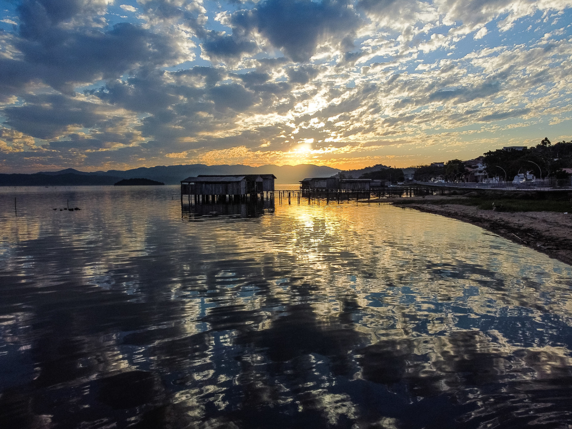 Ranchos de pesca sobre palafitas na Lagoa de Imaruí ao pôr do sol, no Sul de Santa Catarina